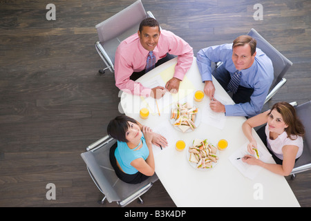 Vier Unternehmer am Konferenztisch mit Sandwiches, Lächeln Stockfoto