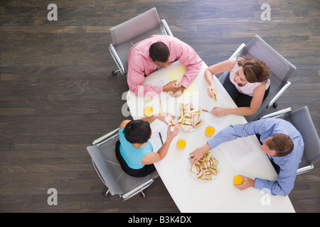 Vier Unternehmer am Konferenztisch mit sandwiches Stockfoto