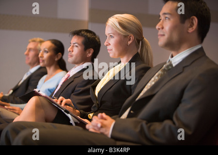 Fünf Geschäftsleute sitzen im Präsentationsraum mit Ablagen Stockfoto