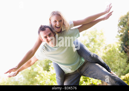 Mann, eine Frau Huckepack Fahrt im freien lächelnd Stockfoto