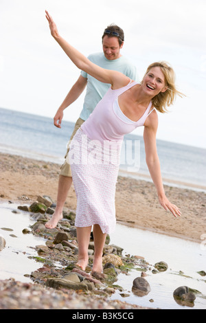 Paar am Strand zu Fuß auf Steinen und lächelnd Stockfoto