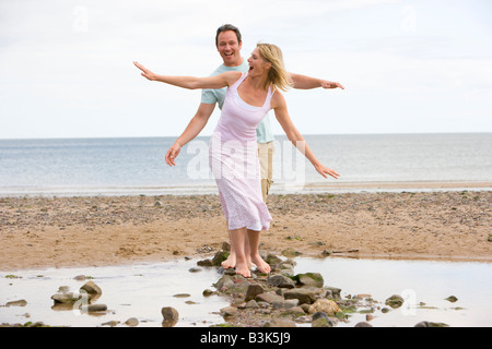 Paar am Strand zu Fuß auf Steinen und lächelnd Stockfoto