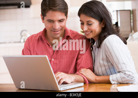 Paar in der Küche mit Laptop lächelnd Stockfoto