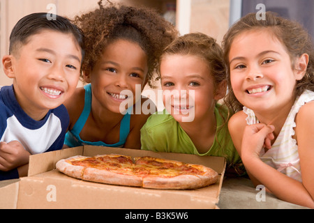 Vier kleine Kinder im Haus mit Pizza lächelnd