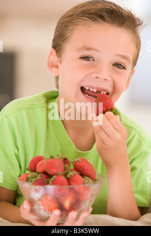 Junge, Essen Erdbeeren im Wohnzimmer lächelnd Stockfoto