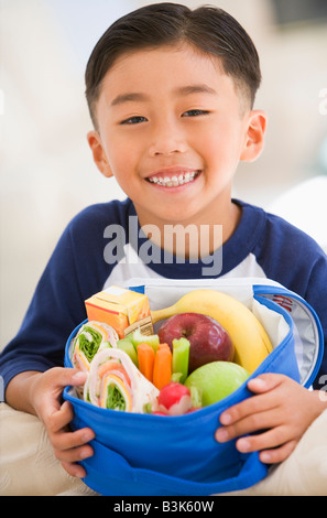 Junge im Innenbereich mit Lunchpaket lächelnd Stockfoto