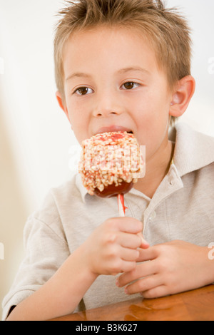 Kleiner Junge drinnen essen Liebesapfel Stockfoto