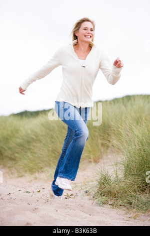 Frau am Strand lächelnd läuft Stockfoto