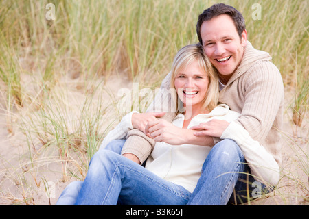 Paar am Strand lächelnd sitzt Stockfoto