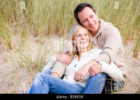 Paar am Strand lächelnd sitzt Stockfoto