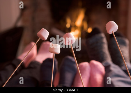 Füße, die Erwärmung auf einen Kamin mit Marshmallows auf sticks Stockfoto