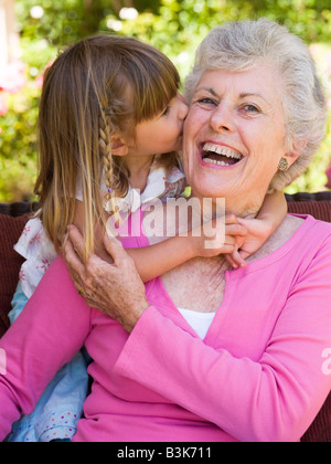 Großmutter immer einen Kuss von Enkelin. Stockfoto