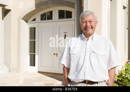 Ältere Mann steht vor seinem Haus Stockfoto