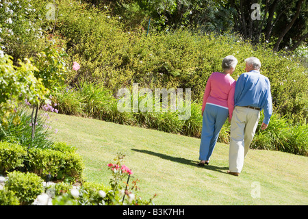 Älteres Paar zu Fuß durch einen Blumengarten Stockfoto