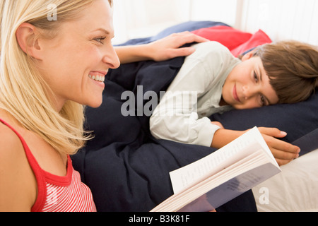 Frau-Lesebuch, junge im Bett lächelnd Stockfoto