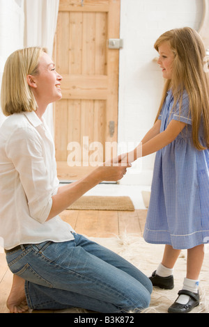 Frau im vorderen Flur junges Mädchen Händchenhalten und lächelnd Stockfoto