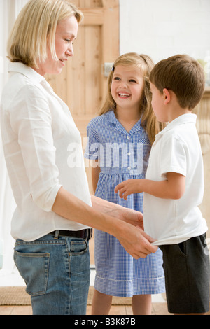 Frau im vorderen Flur mit zwei kleinen Kindern, die lächelnd Stockfoto