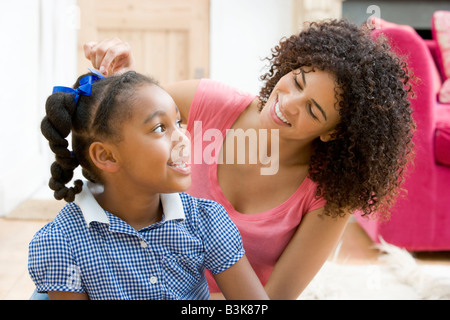 Frau im vorderen Flur Befestigung junge Mädchen an den Haaren und lächelnd Stockfoto