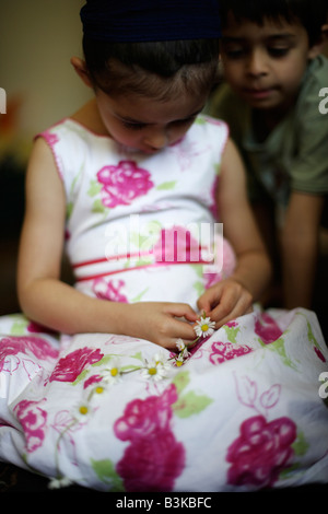 Fünf Jahre altes Mädchen macht Daisy-Chain, Wached von ihrem Bruder Stockfoto