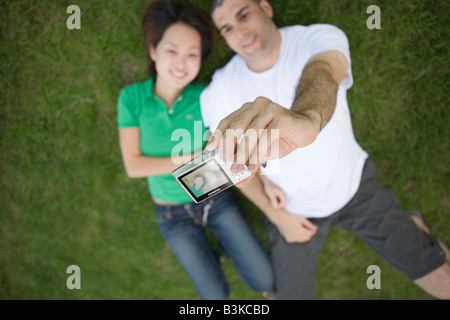 junges Paar Einnahme von digitalen Bild von sich selbst im Gras im freien Stockfoto
