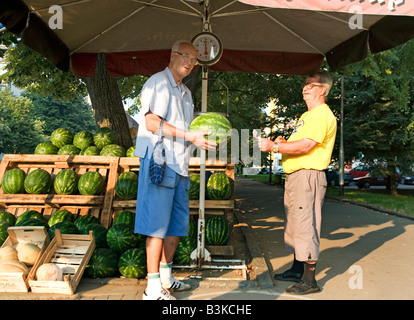 Älterer Mann kauft eine Wassermelone von am Straßenrand Lebensmittelhändler Stockfoto