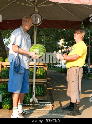 Älterer Mann kauft eine Wassermelone von am Straßenrand Lebensmittelhändler Stockfoto