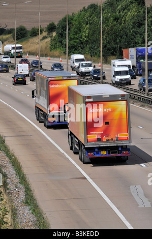 M25 Autobahn zwei von einer Art Sainsburys Supermarkt Lieferwagen im Konvoi Stockfoto