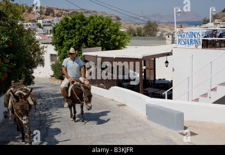 Mann reiten Esel auf der Straße mit Kopfsteinpflaster, Lindos Griechenland Stockfoto