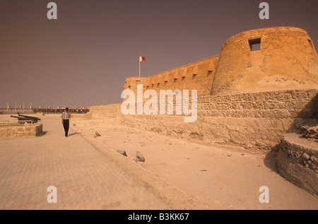 Naher Osten, das Königreich Bahrain (Arabisch: Mamlakat al-Baḥrayn), Fußgänger, die außerhalb der Festung Arad Muharraq Insel. Stockfoto