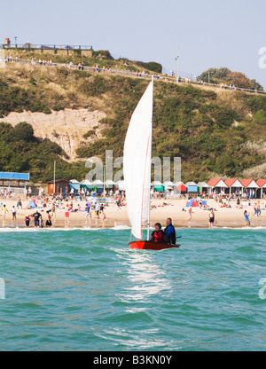 Ein älteres paar Segeln ihre Jolle vor Strand von Bournemouth, Dorset. VEREINIGTES KÖNIGREICH. Stockfoto