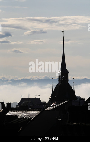 Silhouette von einem Kirchturm in der Berner Altstadt, Schweiz. Die Schweizer Alpen sind im Hintergrund zu sehen. Stockfoto
