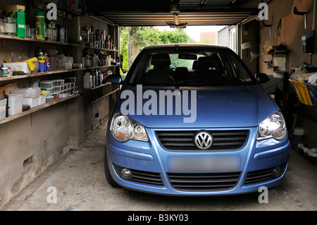 Volkswagen VW Polo Auto in angebautem Haus Wohneigentum geparkt Garagenregale für die Lagerung von verschiedenen Haushaltsgegenstand & Werkzeuge England GB Stockfoto