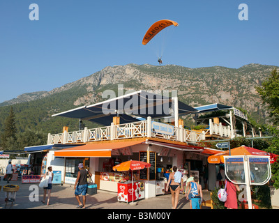 Gleitschirm fliegen über dem beliebten Buzz Bar im Dorf von Ölüdeniz. Provinz Mugla, Türkei. Stockfoto