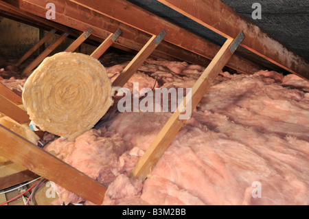 Wohnraum Loft mit niedriger Dachneigung, die Holzdächer zeigen, die Glasfaser verteilen und eine zusammengerollte Dämmdecke über England Großbritannien übrig geblieben ist Stockfoto