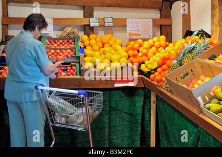 Reife Frau Shopping Interior Einzelhandelsgeschäft Calcott Hall Farm Shop Obst-Produktion Ausstellung in alten großen umgebauten Scheune Brentwood Essex England Großbritannien Stockfoto