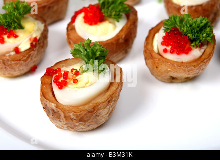 Eine Platte mit Wachteln Ei Häppchen sind die Eizellen in kleine gebackene Pellkartoffeln mit Seehasen-Kaviar und ein Bund Petersilie garniert Stockfoto