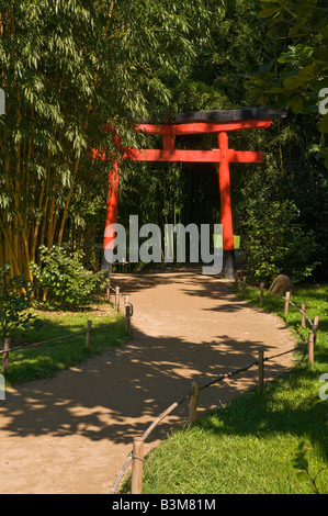 Leuchtend rote japanische Torii Tor in einem Garten in Frankreich. Stockfoto