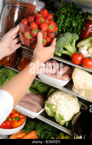 FRAU NEHMEN SCHALE MIT FRISCHEN ERDBEEREN AUS DEM KÜHLSCHRANK Stockfoto