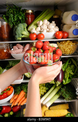 FRAU NEHMEN SCHALE MIT FRISCHEN ERDBEEREN AUS DEM KÜHLSCHRANK Stockfoto