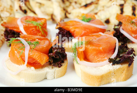 Eine Platte mit geräuchertem Lachs Häppchen auf französisches Brot garniert mit Salat Dill und eine Zwiebel-ring Stockfoto