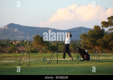 Mann üben Golf auf einer driving range - durch das schwingen nach Stockfoto