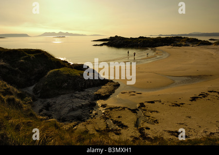 Paare, die Hunde auf einem sandigen Strand bei Sonnenuntergang, Camusdarach, Schottland Stockfoto