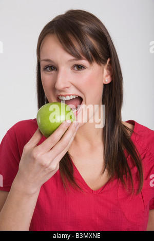 Junge Frau hält einen Apfel, Porträt Stockfoto