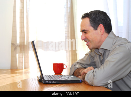 Man sitzt an seinem Schreibtisch mit einem Laptop schauen glücklich Stockfoto