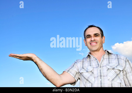 Glückliche Mann mittleren Alters gestikulieren auf blauen Himmelshintergrund Stockfoto