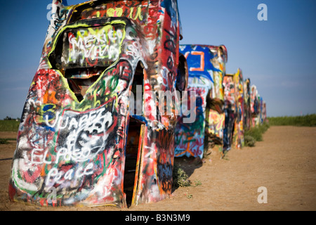 Autos stecken in den Boden und spritzlackiert mit Graffiti auf der Seite der i-40 auf der Cadillac Ranch in Amarillo, Texas. Stockfoto