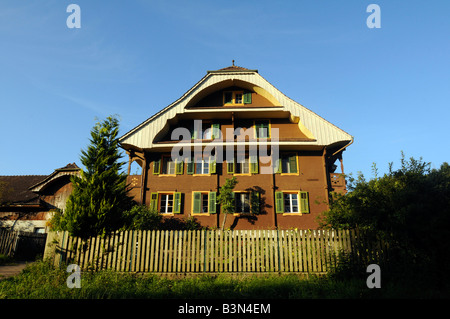 Ein typisches Schweizer Haus inmitten der Natur des ländlichen Raums, Baum, Berge und Nationalflagge; Foto aufgenommen in der Zentralschweiz Stockfoto