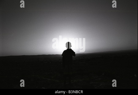 eine Silhouette eines Beduinen-Kindes zu Fuß in die Sonne in der Negev-Wüste in Israel. Stockfoto