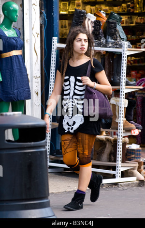 London Camden Lock Market hübsche junge weibliche Teenager brunette t-shirt Skelett zerrissene Strumpfhosen violett Umhängetasche walking Pflaster street scene Stockfoto