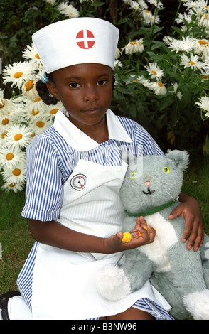 Kleine schwarzes Mädchen in eine Krankenschwester Uniform geben ihr Spielzeug Katze eine Injektion. Stockfoto